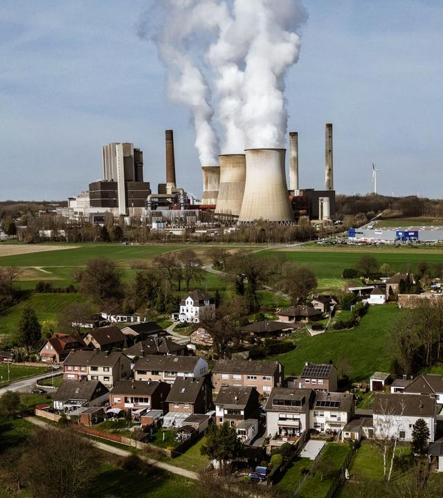 Das RWE Braunkohlekraftwerk Weisweiler im Hintergrund, mit Wohnhäusern mit Vordergrund.