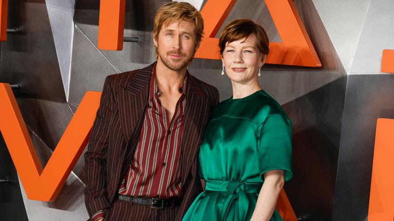 Ryan Gosling und Sandra Hüller vor einer Wand mit orangen und grauen Elementen.