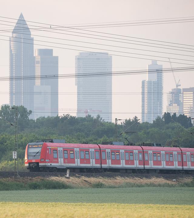 Eine S-Bahn fährt vor der Frankfurter Skyline.