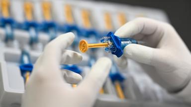 Ein Mitarbeiter von Vetter Pharma kontrolliert in der Produktion die korrekte Montage von Anbauteilen an einer Spritze.