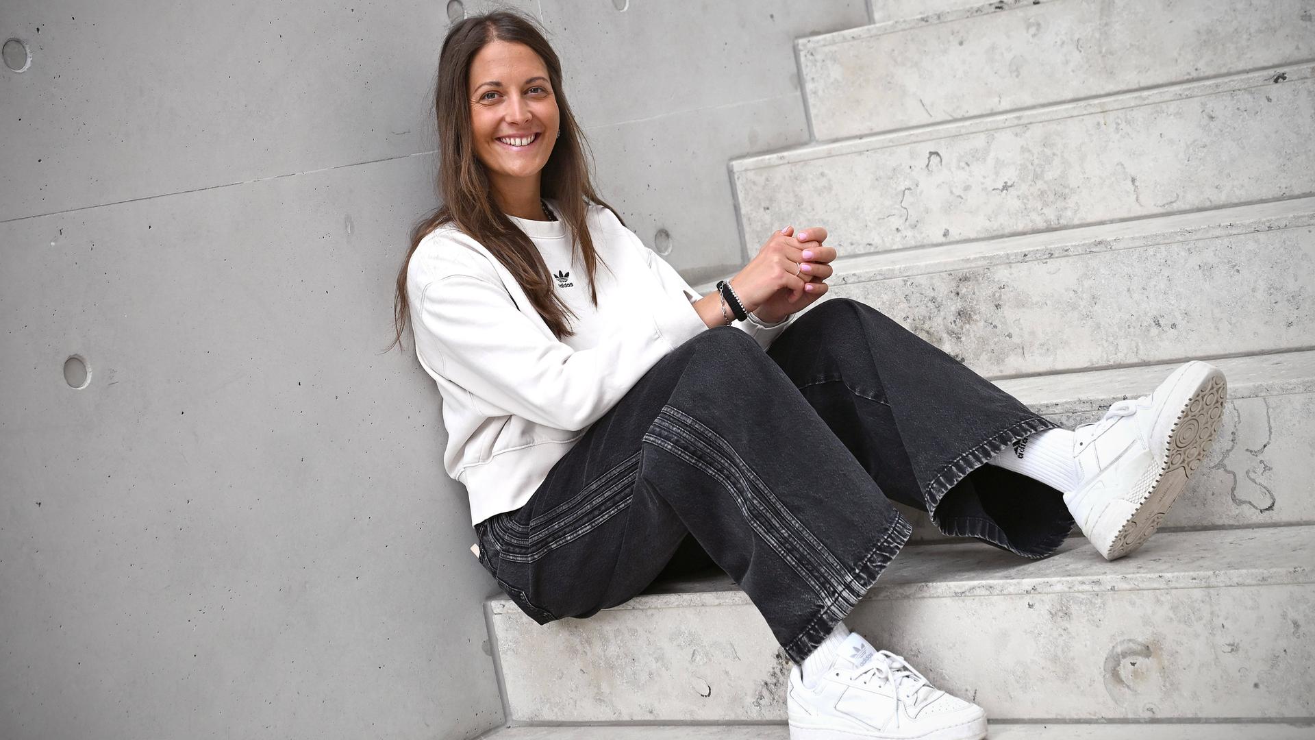 Die deutsche Freestyle-Skierin Sabrina Cakmakli sitzt lächelnd auf einer Treppe