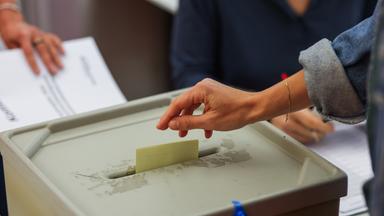 Eine Frau wirft ihren Stimmzettel in die Wahlurne