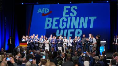 06.09.2026, Sachsen-Anhalt, Magdeburg: Funktionäre der AfD stehen bei der Wahlparty der AfD im Alten Theater vor dem Schriftzug "Es beginnt hier" auf der Bühne.