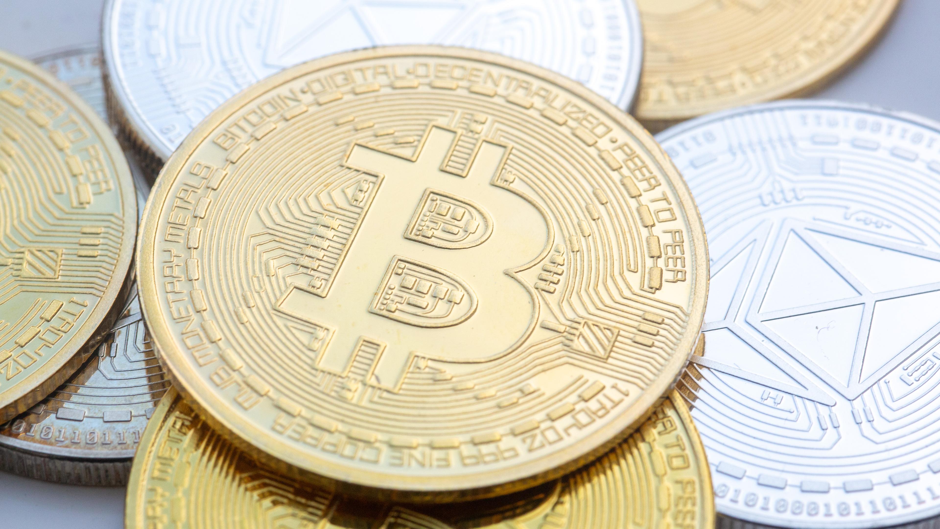 Bitcoin (M) und Ethereum-Münzen sind auf einem Tisch angeordnet.