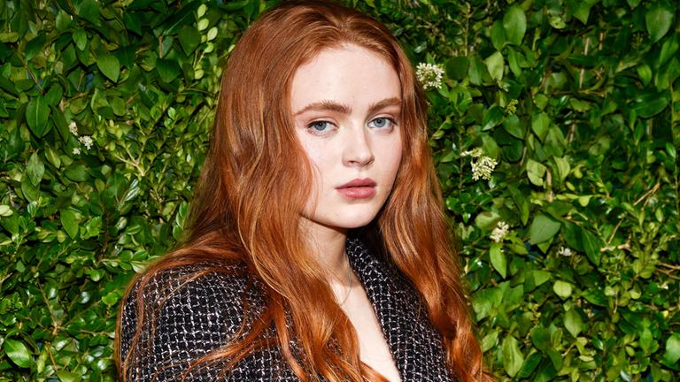Sadie Sink ist vor einer Pflanzenwand zu sehen und schaut in die Kamera.