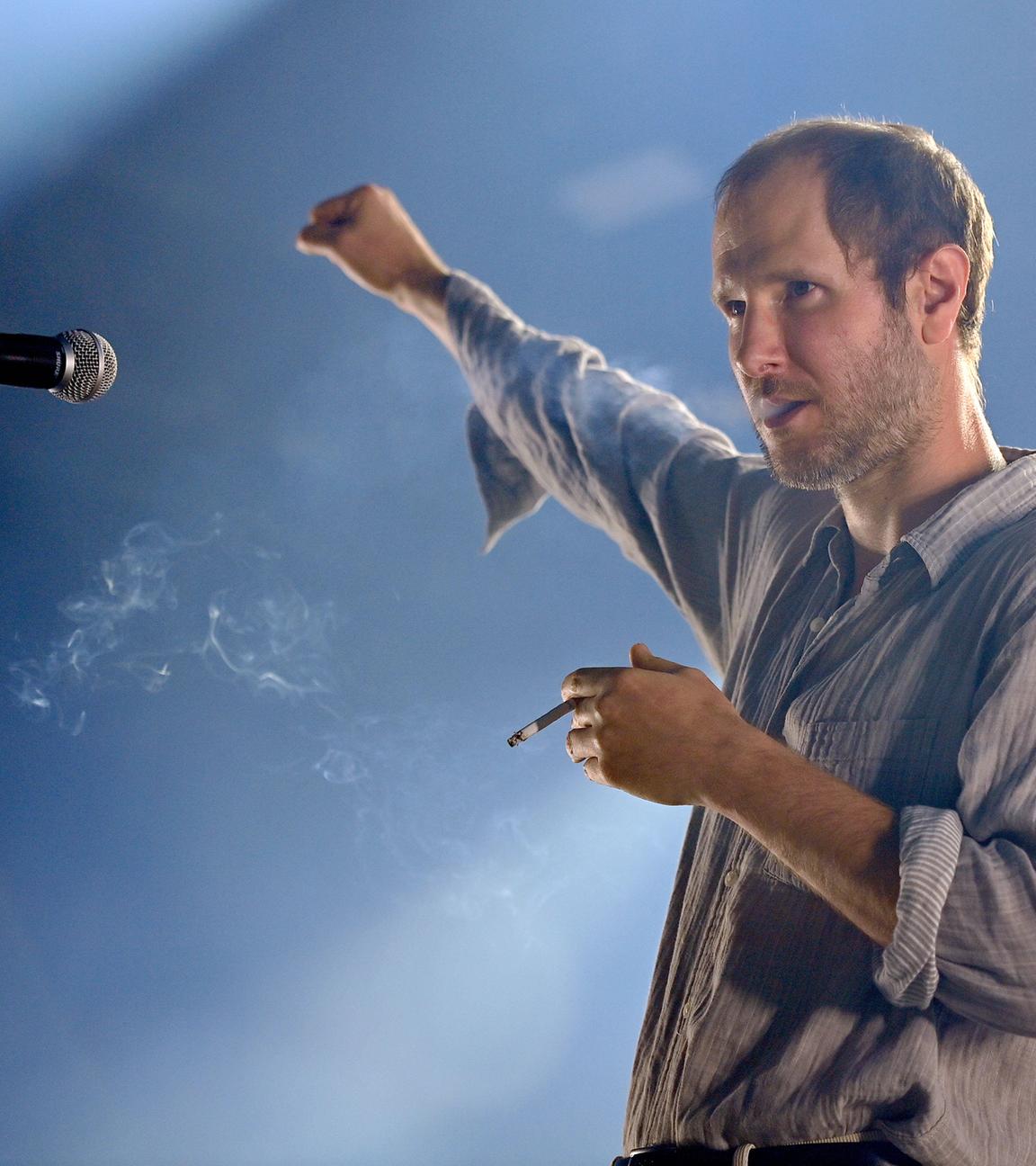 Marco Wanda, Frontsänger der Wiener Band Wanda, im Scheinwerferlicht auf einer Bühne.