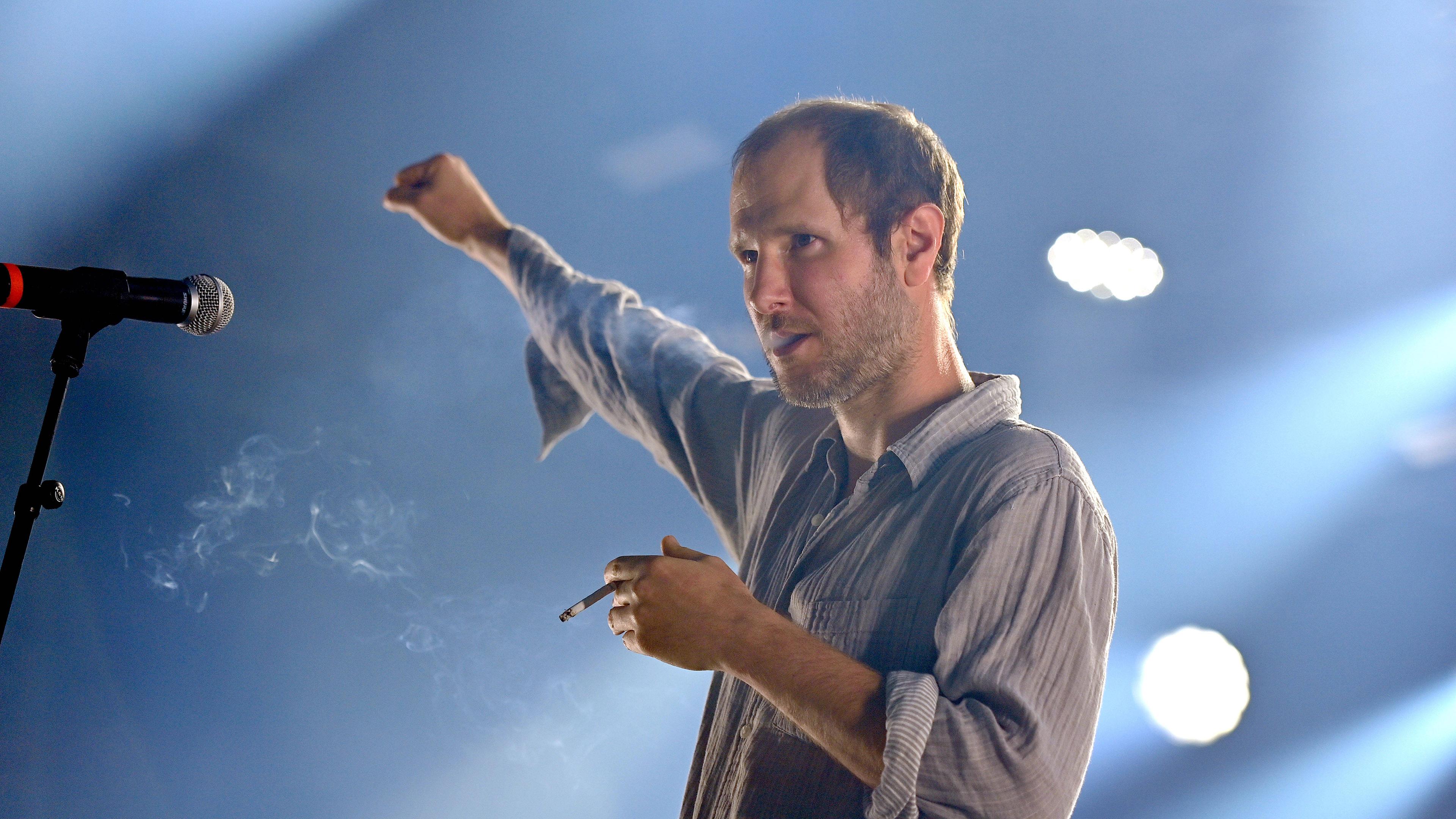 Marco Wanda, Frontsänger der Wiener Band Wanda, im Scheinwerferlicht auf einer Bühne.