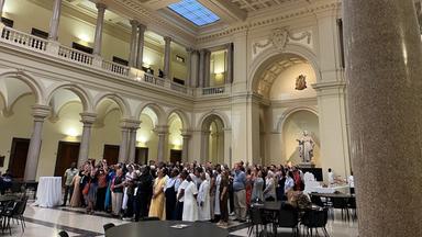 Eine Gruppe von Personen steht eng aneinander in der Mitte einer Kirche