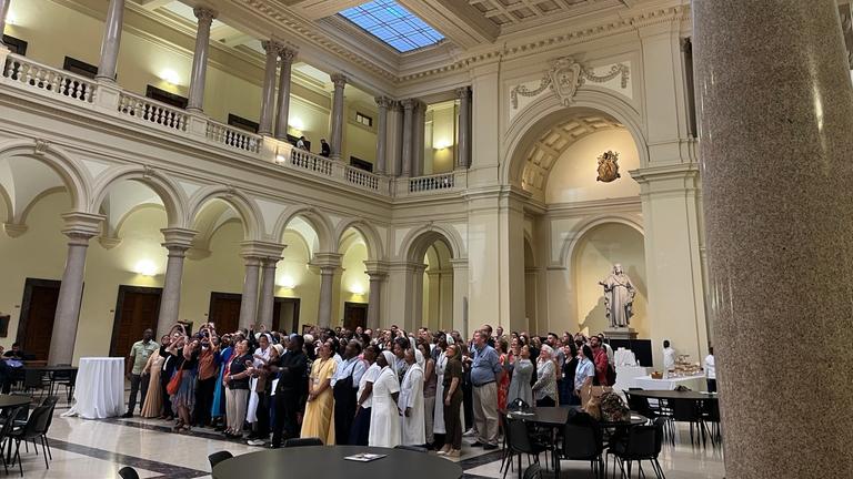 Eine Gruppe von Personen steht eng aneinander in der Mitte einer Kirche