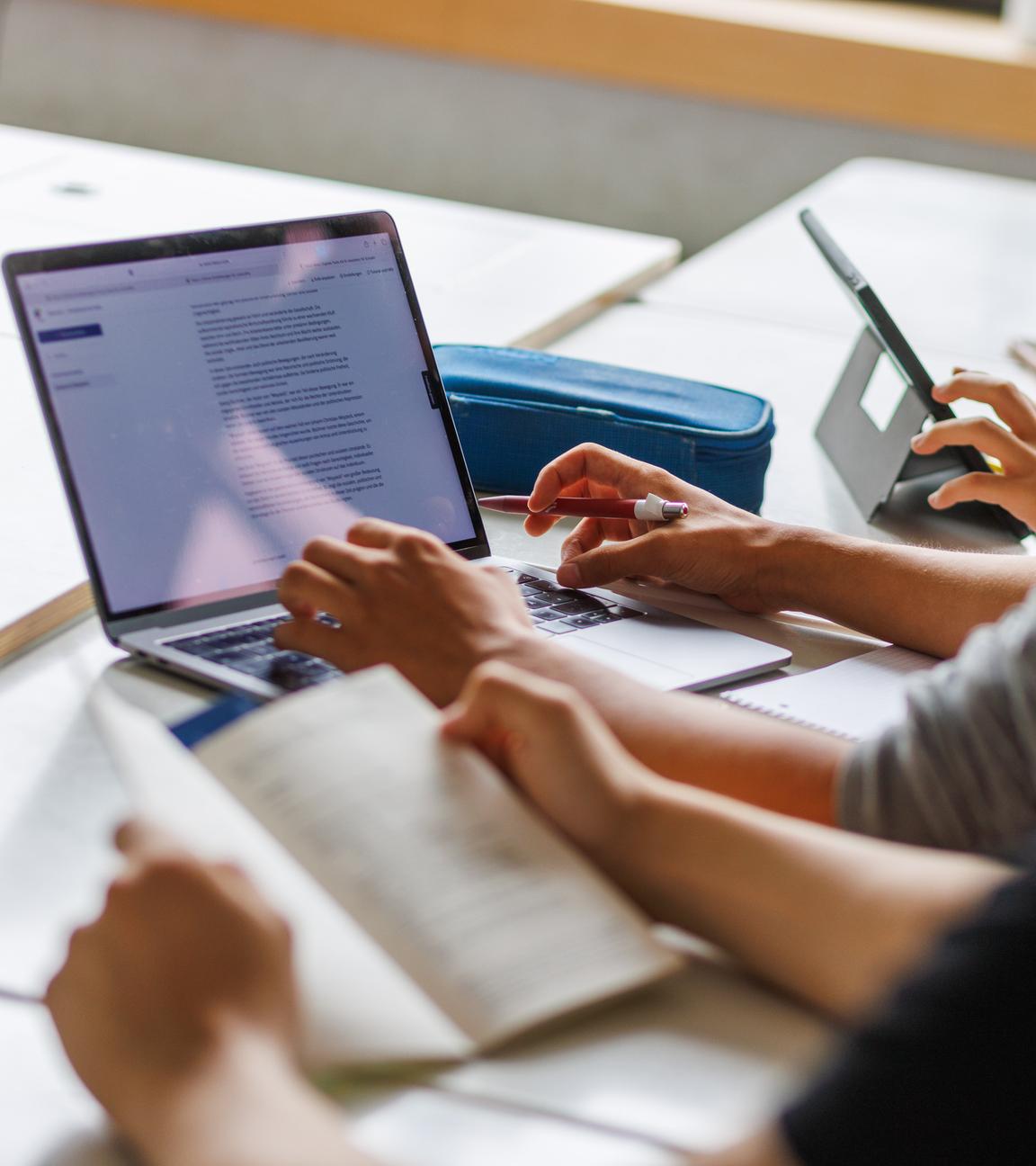 Schüler sitzen vor einem Computer und benutzen ein KI-Tool. 