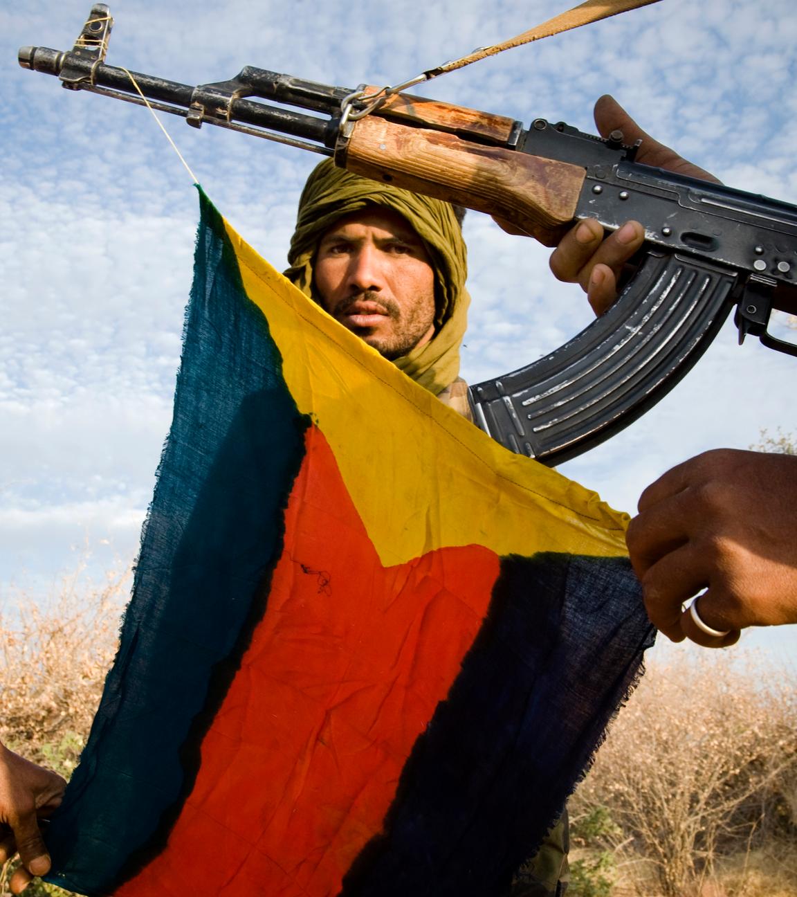 Söldner in der Sahelzone posieren mit Mali-Flagge und AK-47 Sturmgewehr.