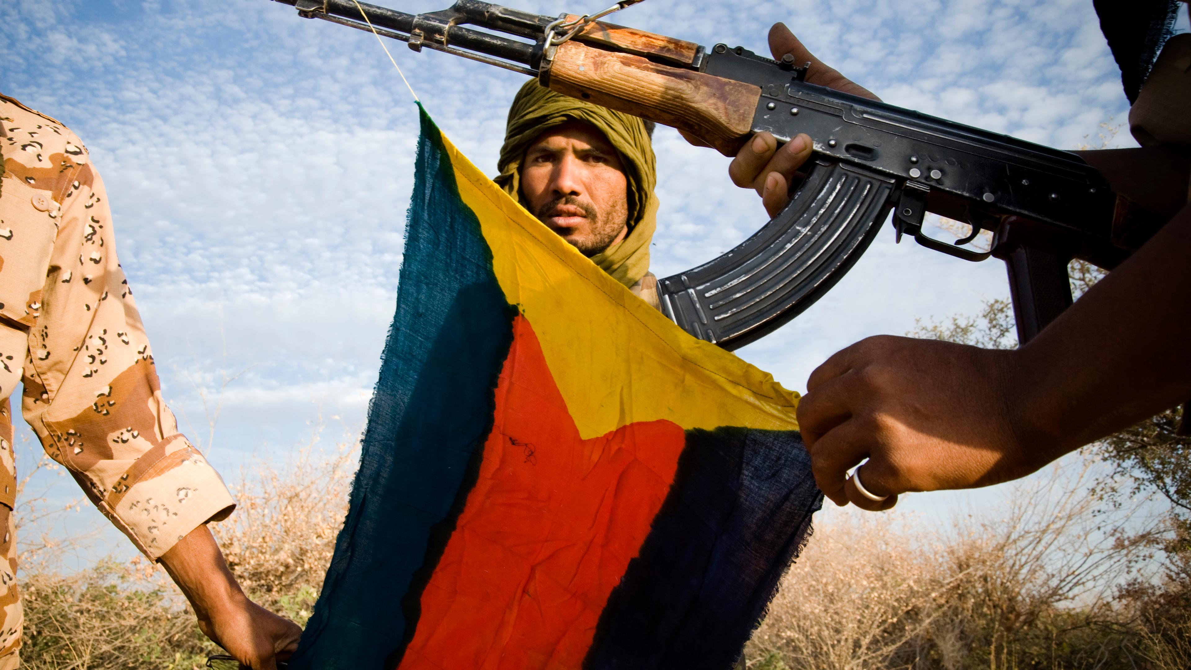 Söldner in der Sahelzone posieren mit Mali-Flagge und AK-47 Sturmgewehr.