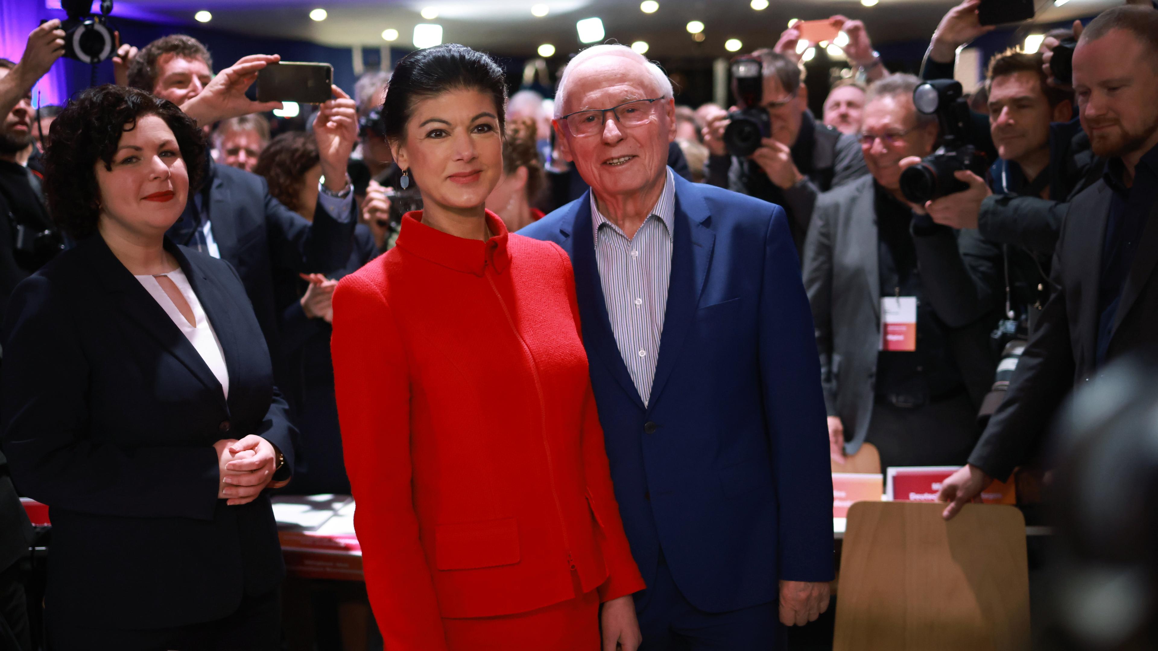 Sahra Wagenknecht mit Oskar Lafontaine und Amira Mohamed Ali auf dem Gründungsparteitag des BSW. Im Hintergrund stehen Fotografen.