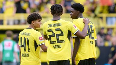 Mathis Albert (Borussia Dortmund), Joane Gadou (Borussia Dortmund) und Mussa Kaba (Borussia Dortmund) stehen nebeneinander im Stadion (v.l.). 