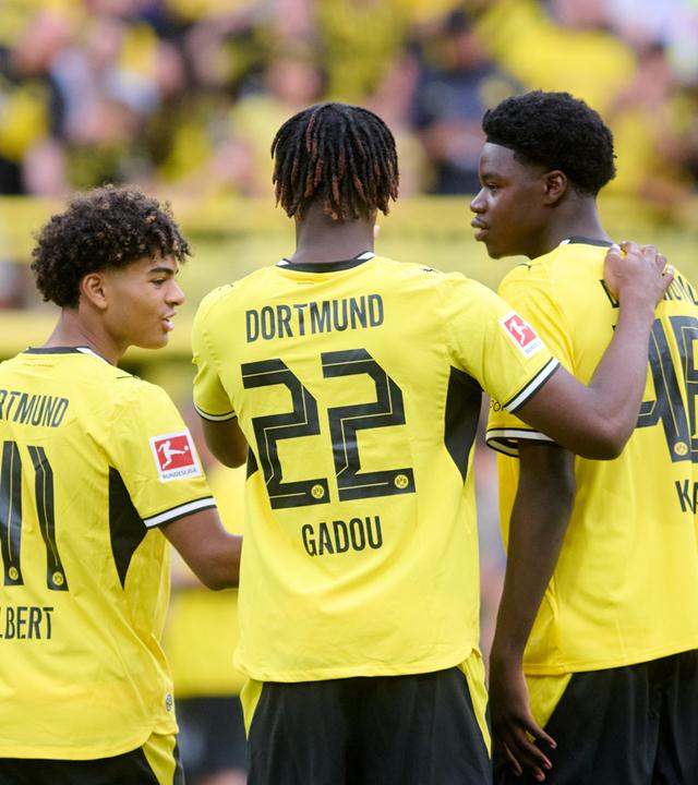 Mathis Albert (Borussia Dortmund), Joane Gadou (Borussia Dortmund) und Mussa Kaba (Borussia Dortmund) stehen nebeneinander im Stadion (v.l.). 