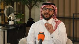 Salman Al-Ansari se sienta en un sillón durante una entrevista y habla por el micrófono.