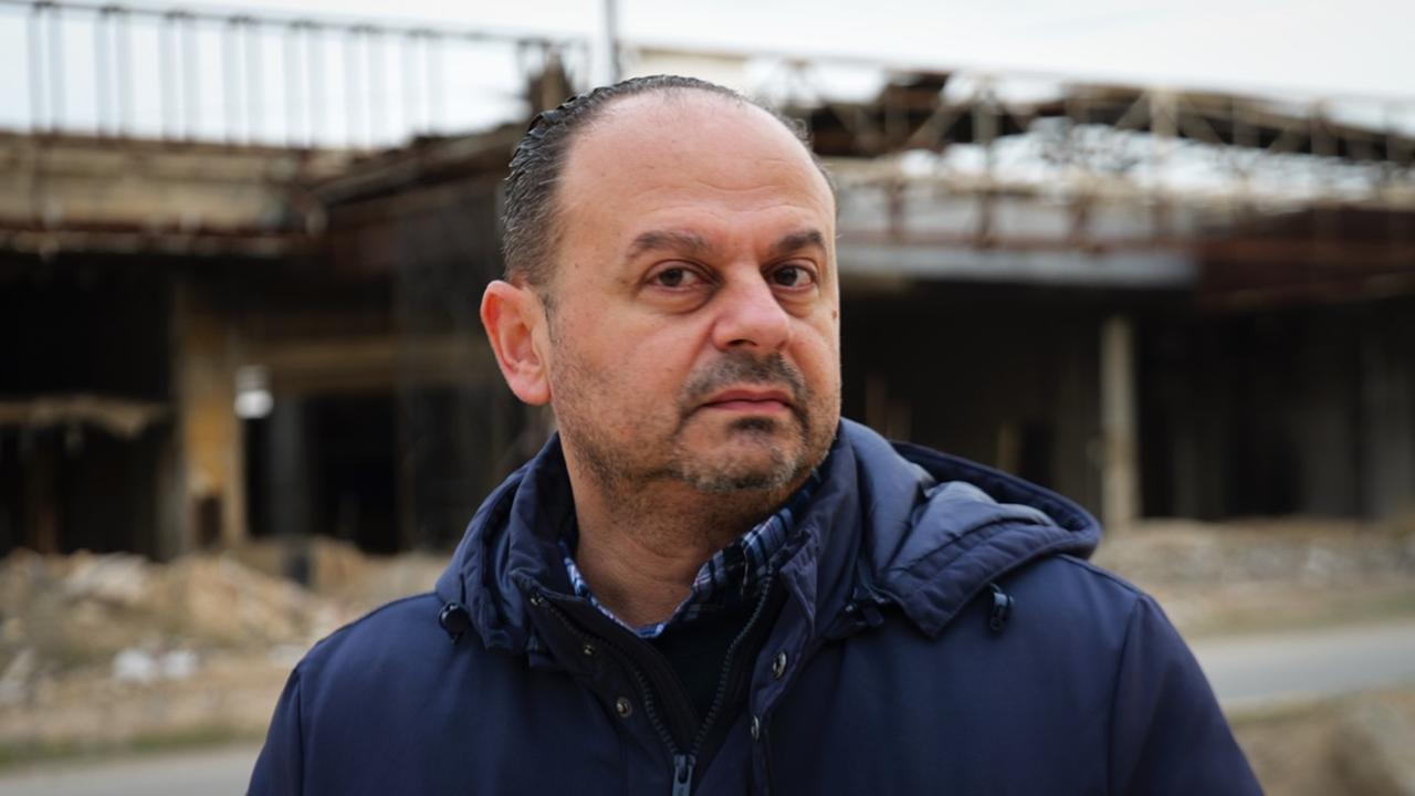 Samir Kazma steht vor einem zerstörten Gebäude.