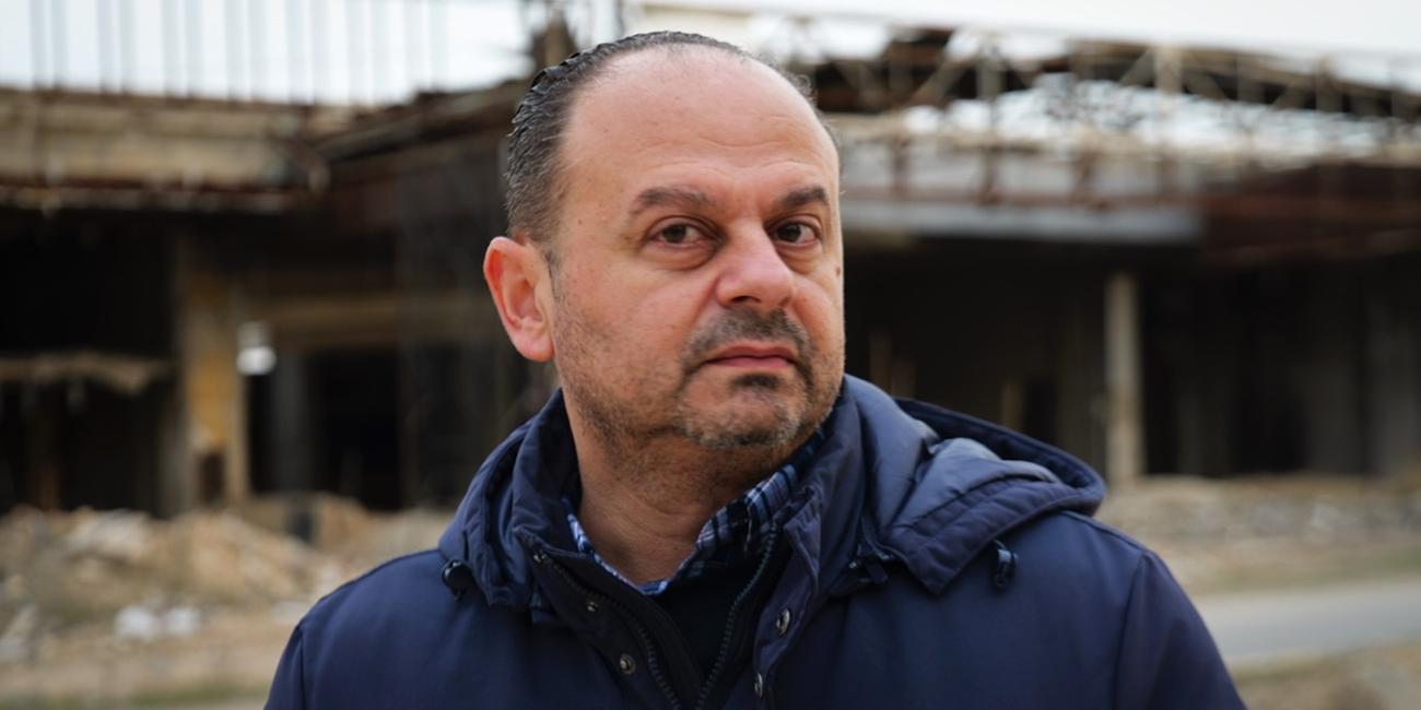 Samir Kazma steht vor einem zerstörten Gebäude.