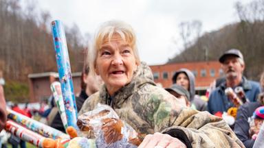 Ein Kind und eine Frau stehen an einer Absperrung und lächeln.