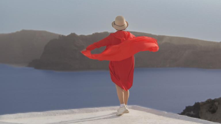 Frau in Griechenland mit roter Tunika und Sonnenhut