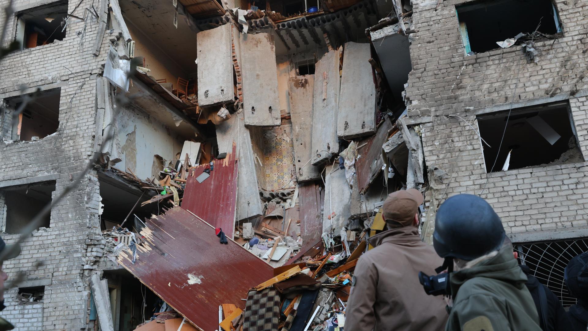 Vor einem zerstörten Wohnheim in Saporischschja stehen Rettungskräfte. 
