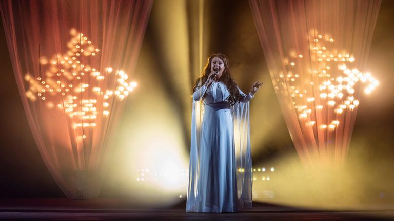 Sarah Brightman steht in einem eleganten, bodenlangen Abendkleid mit transparenten Stoffärmeln auf der Bühne bei "Die große Sommerparty".