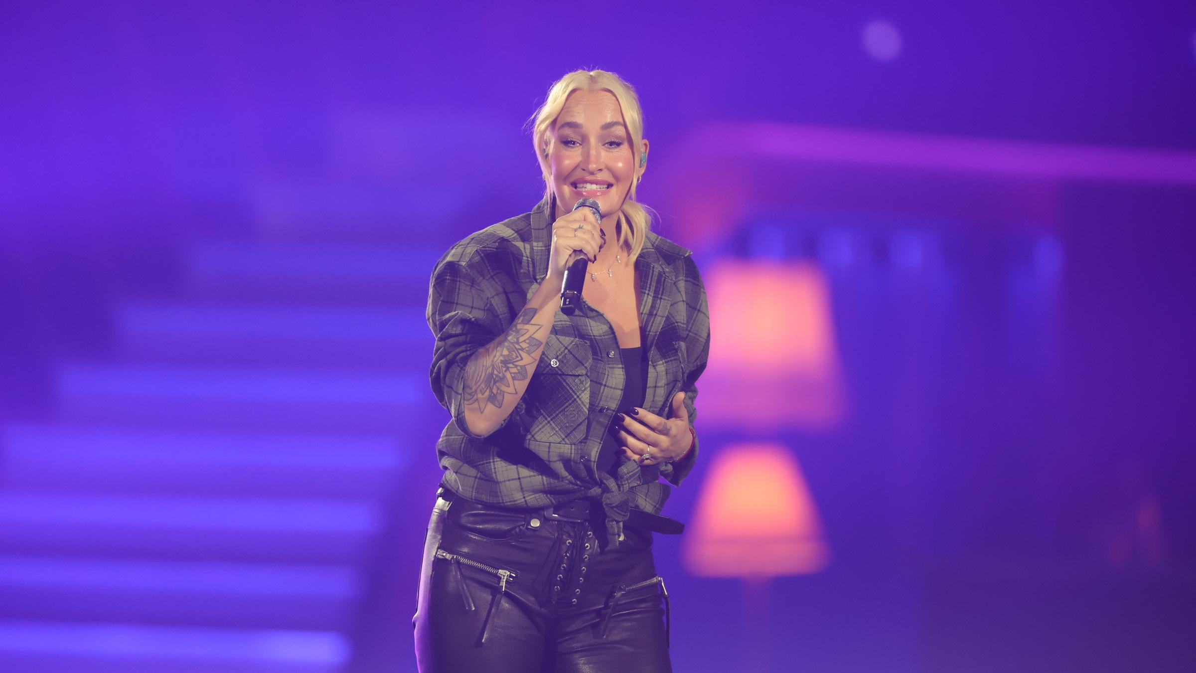 Sarah Connor ist während einer Performance zu sehen mit einem Mikrofon in der Hand.