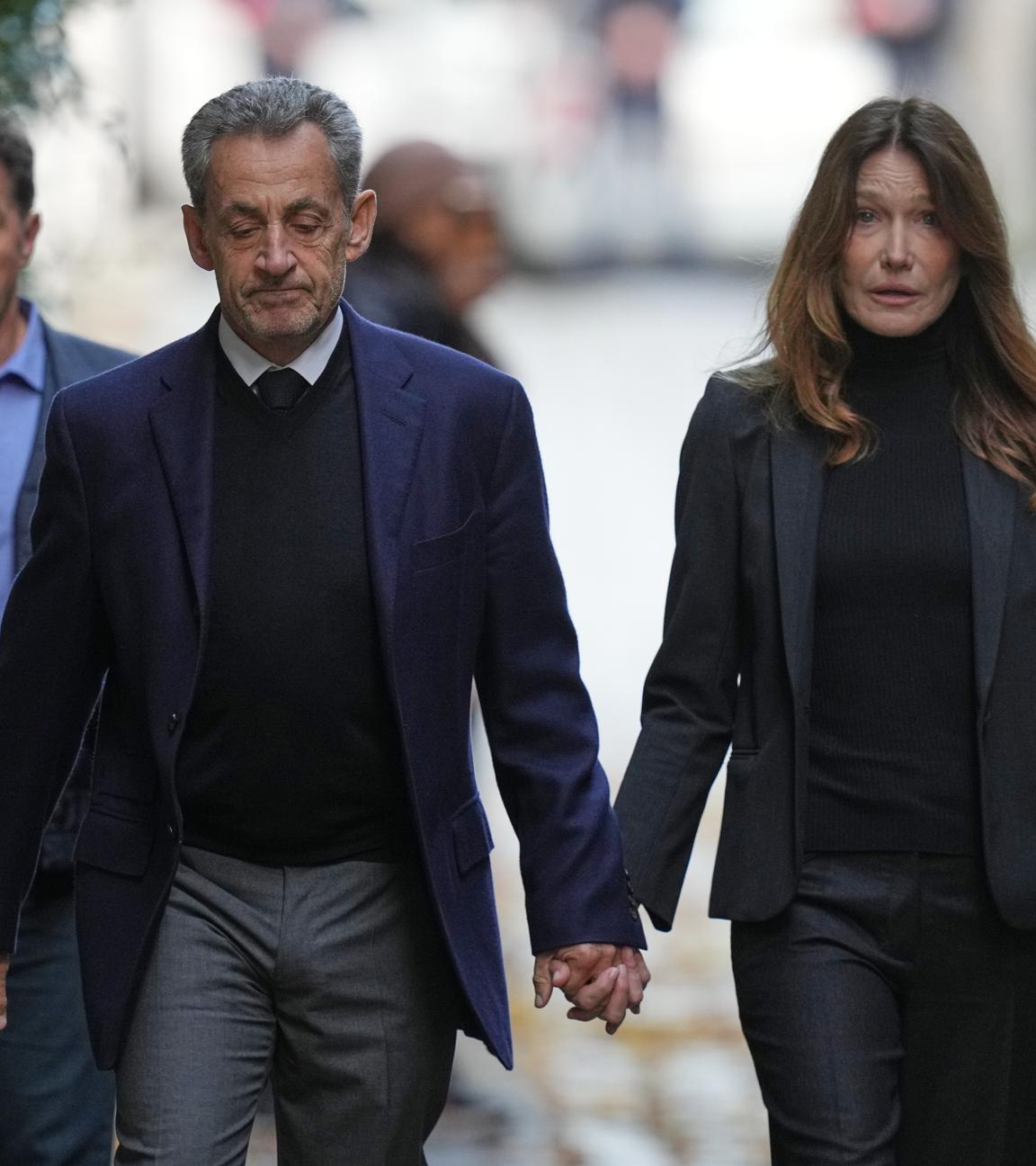 Nicolas Sarkozy und seine Frau halten sich an der Hand.