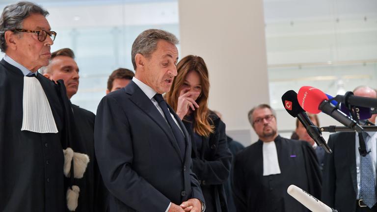 Den verurteilten ehemaligen Präsidenten Sarkozy im Gericht in Paris. Um ihn herum sind viele Menschen von der Presse