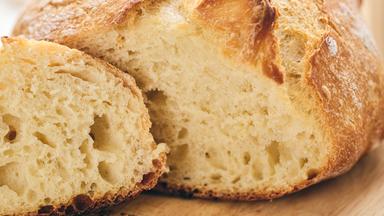 Geschnittenes handwerklich hergestelltes Sauerteigbrot mit luftiger Krume auf einem Holzbrett