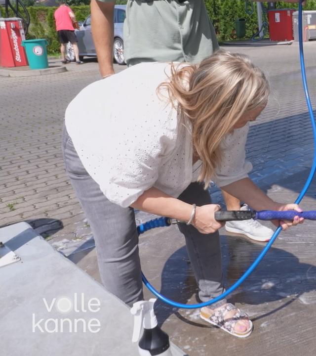 Frau bespritzt Felgen mit Hochdruckreiniger