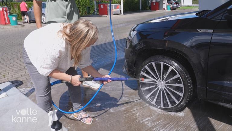 Frau bespritzt Felgen mit Hochdruckreiniger