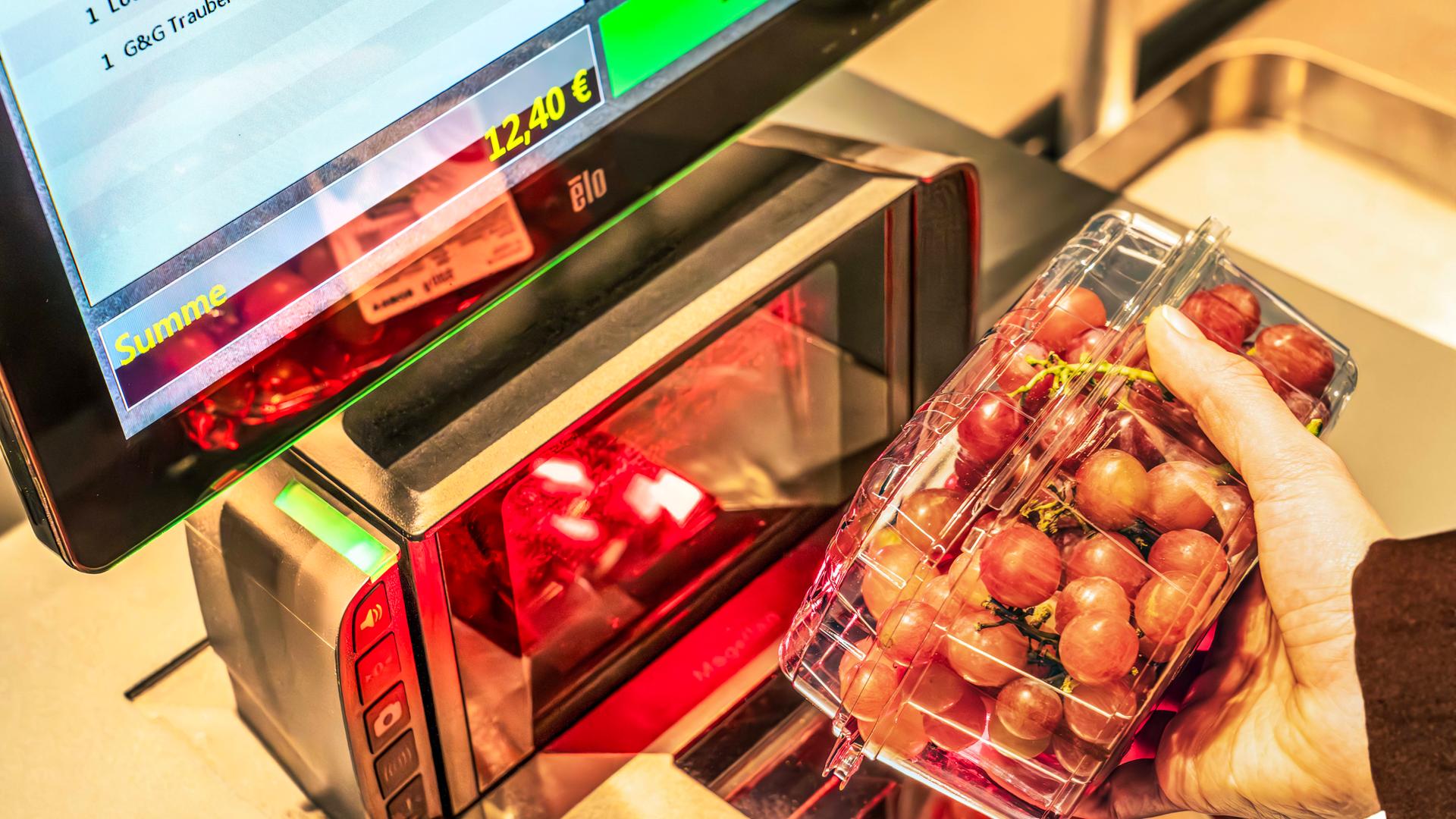 Ein Kunde scannt eine packung Trauben an einer Selbstbedienungskasse.