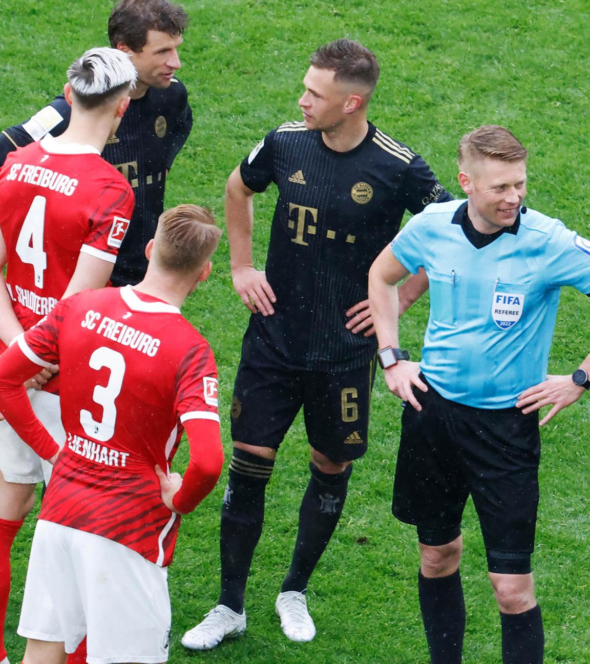 02.04.2022, Baden-Württemberg, Freiburg im Breisgau: Fußball: Bundesliga, SC Freiburg - Bayern München, 28. Spieltag, Europa-Park Stadion: Schiedsrichter Christian Dingert (in blau) steht gemeinsam mit Spielern dass SC Freiburg und des FC Bayern München während einer Spielpause auf dem Feld.