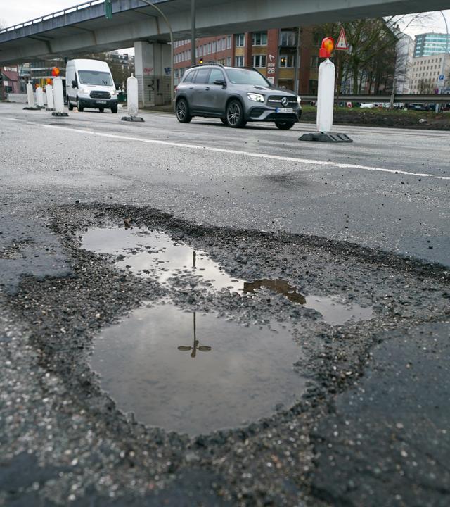 Metergrosse Schlagloecher sind auf einer Straße in Hamburg zu sehen.