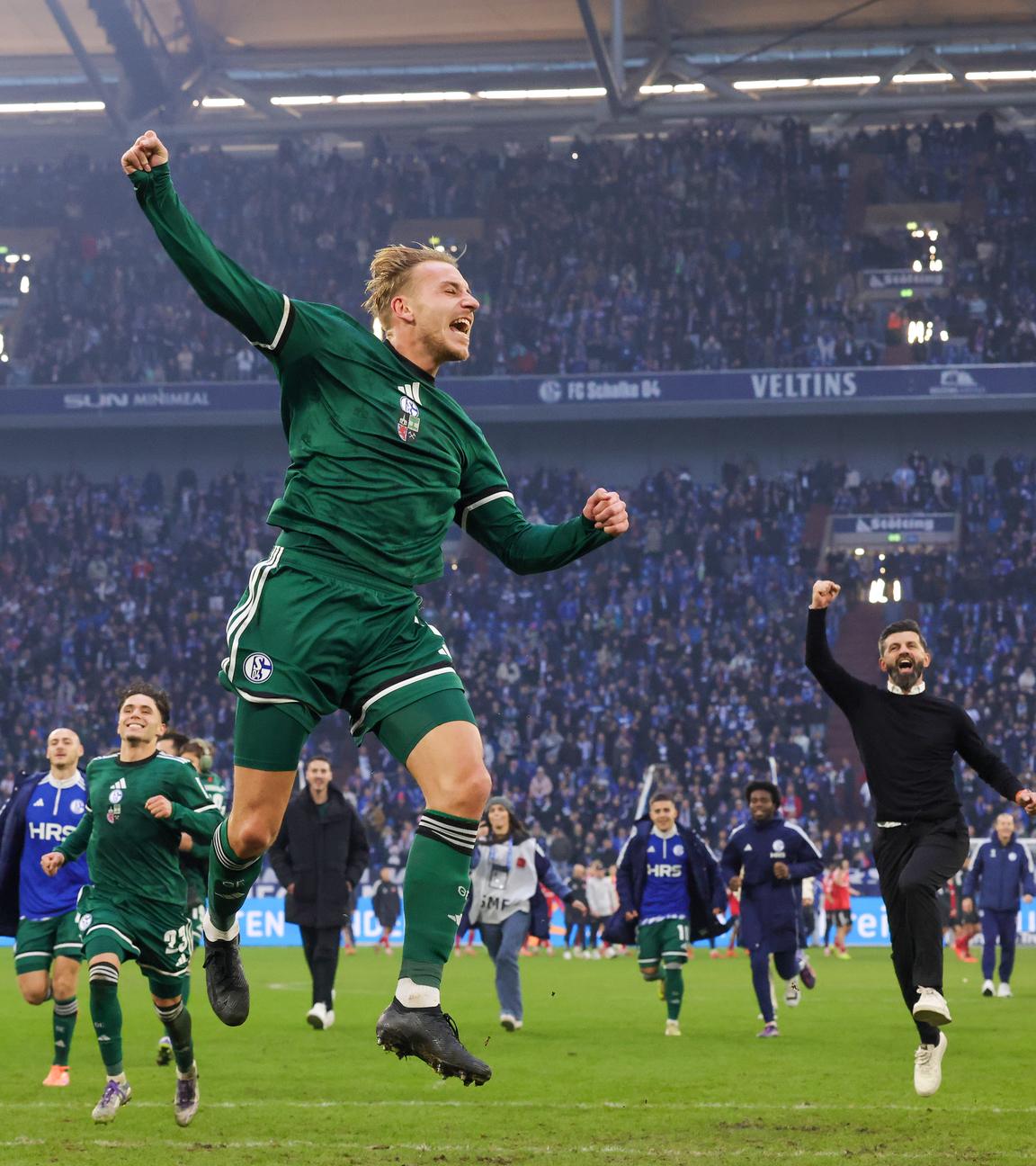 Nach dem Heimsieg gegen den 1.FC Nürnberg rennt der Schalker Abwehrspieler Timo Becker mitsamt der Mannschaft und Trainer Muslic Miron jubelnd zur Schalker Kurve