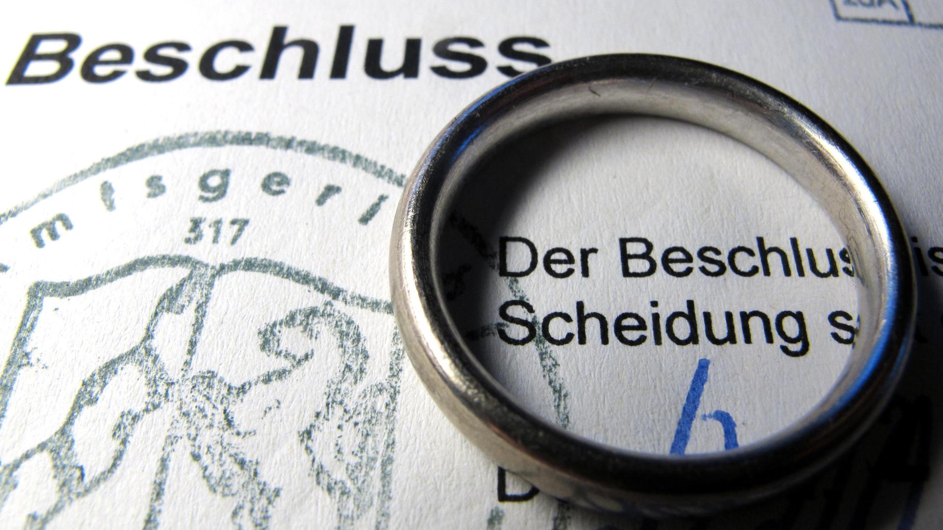 Auf einem Scheidungsformular liegt ein Ehering.