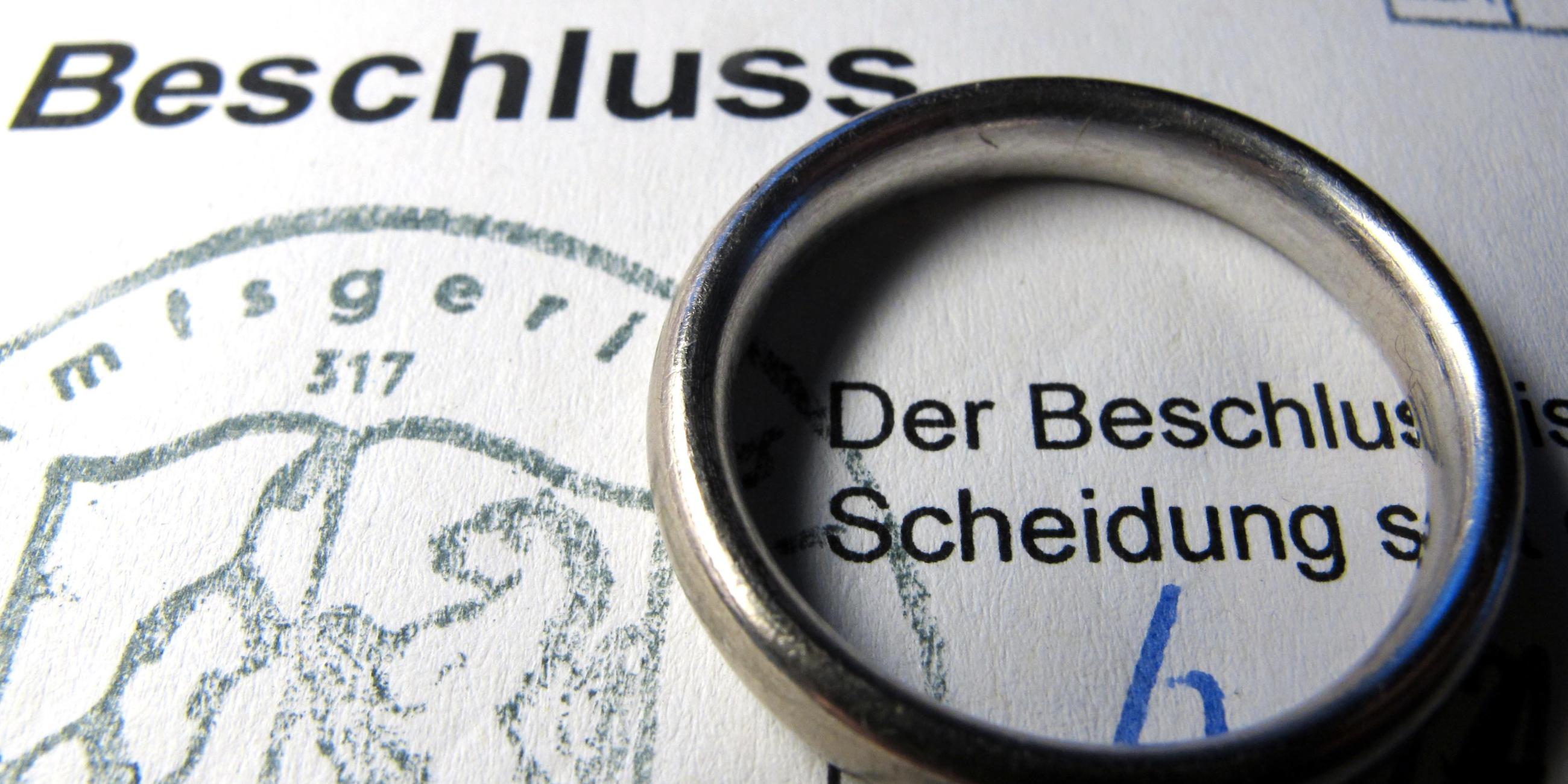 Auf einem Scheidungsformular liegt ein Ehering.