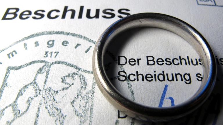 Auf einem Scheidungsformular liegt ein Ehering.