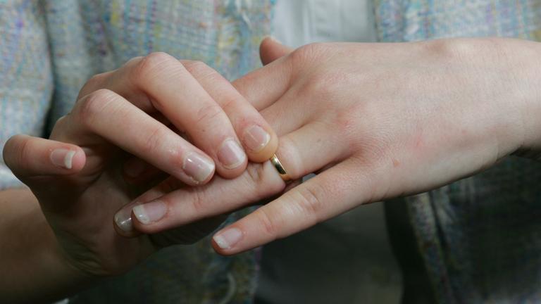 Eine Frau zieht ihren Ehering vom Finger.