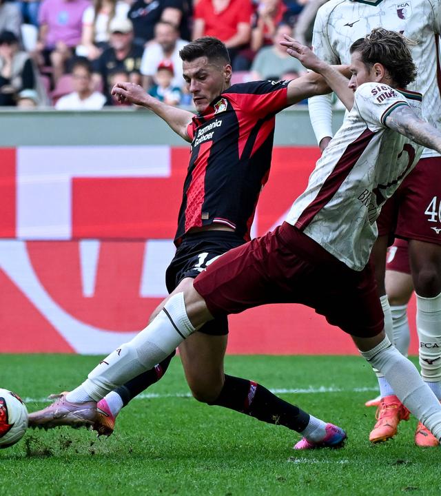 Leverkusens Stürmer Patrick Schick kämpft mit seinem Augsburger Gegenspieler Calvin Brackelmann um den Ball