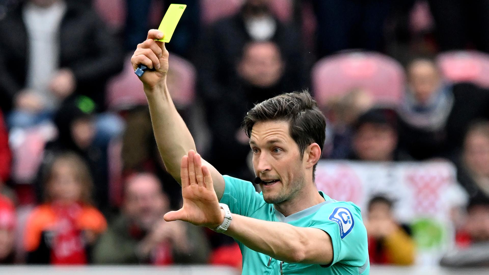 Schiedrichter Matthias Jöllenbeck zeigt die gelbe Karte (Archivbild)