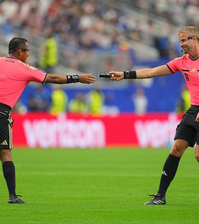 Schiedsrichter Barton aus El Salvador bekommt das Freistoßspray von einem Assistenten gereicht.