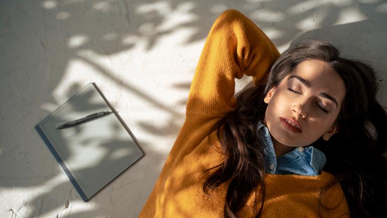 Junge Frau entspannt sich zu Hause auf dem Boden.