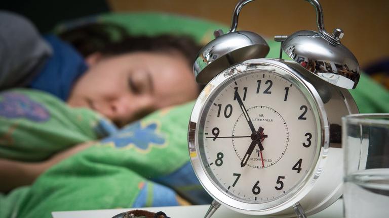 Wecker steht neben schlafender Frau