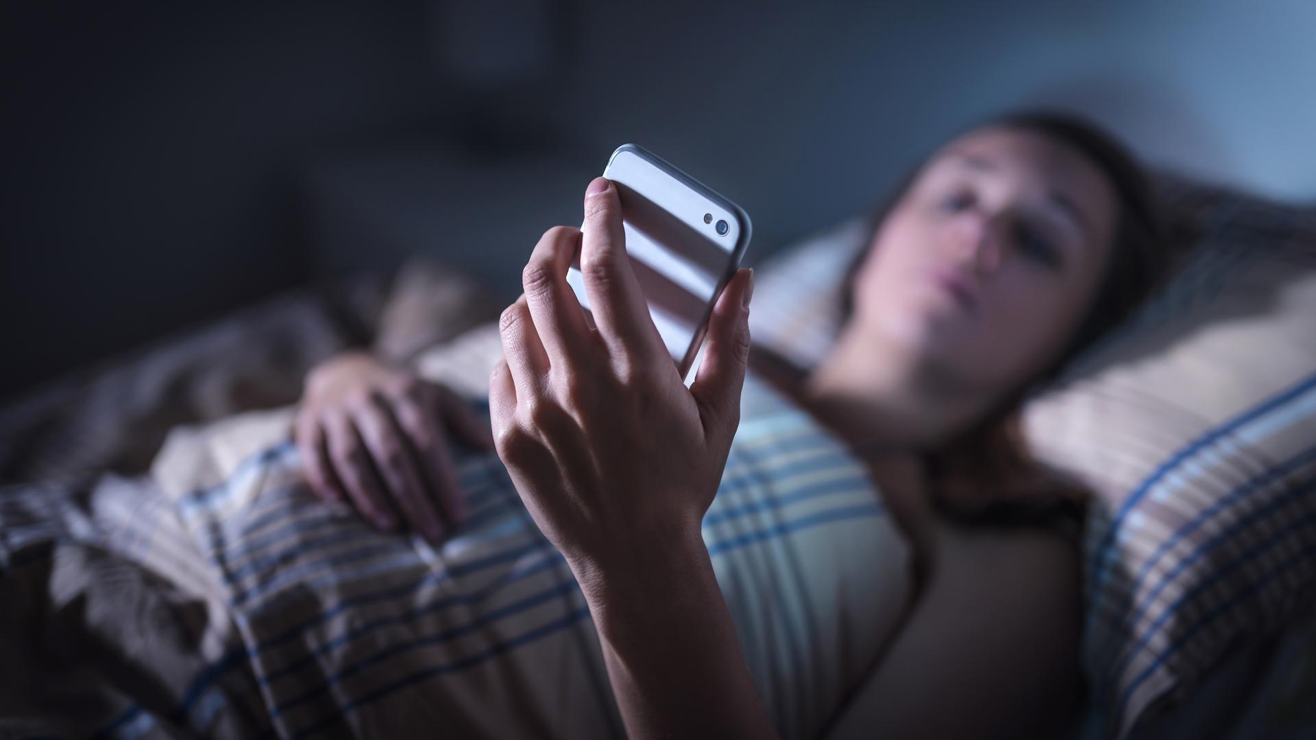 Illustration: Frau schaut im Bett auf Handy, aufgenommen am 8.11.2018