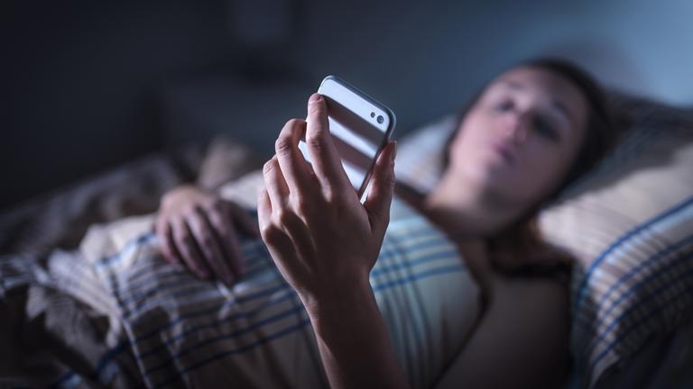 Illustration: Frau schaut im Bett auf Handy, aufgenommen am 8.11.2018