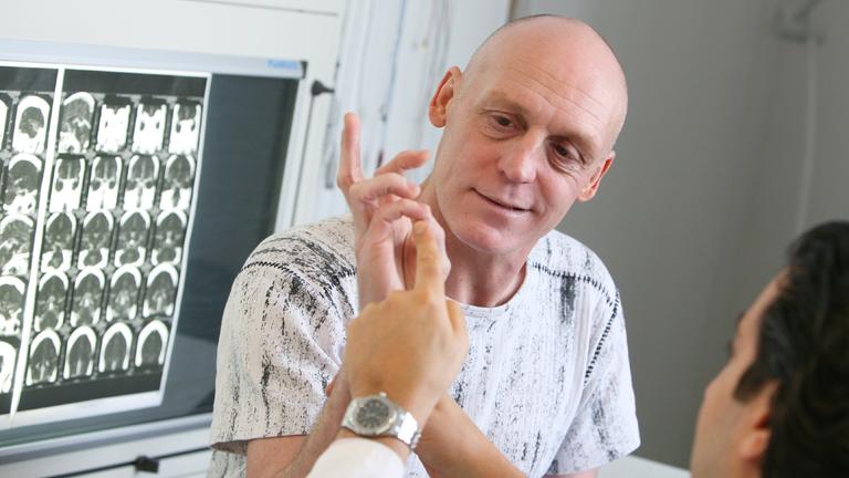Ein Neurochirurg überprüft die Motorik der Hände bei einem Schlaganfall-Patient.