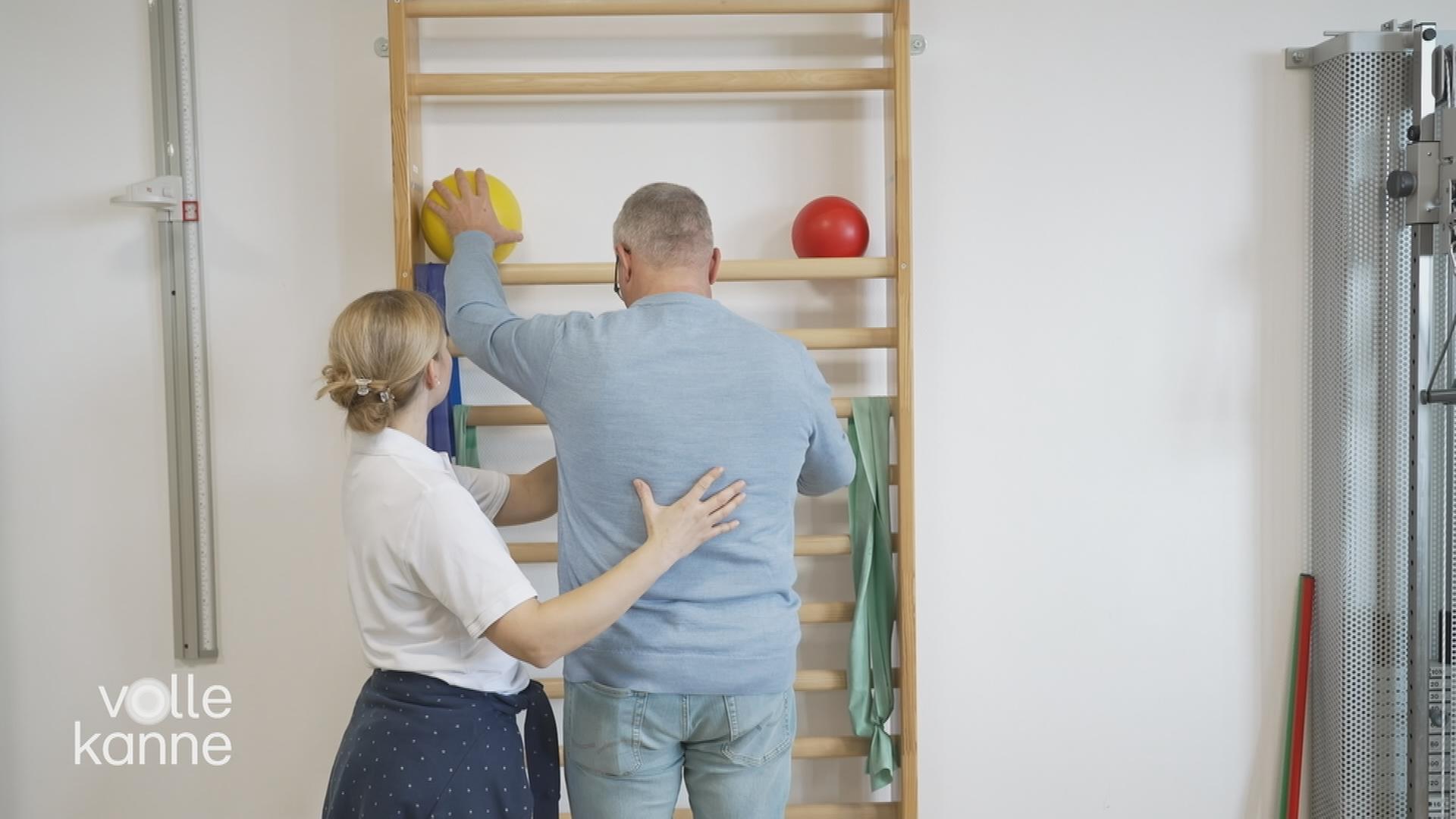 Eine Frau hilft einem Mann bei Krankengymnastik-Übungen.