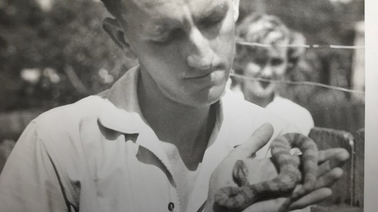 Schwarz-Weiß-Foto von Kevin Budden, der eine Schlange in den Händen hält.
